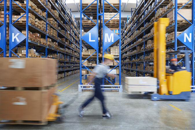 An employee moves through a distribution centre filled with boxes on shelves